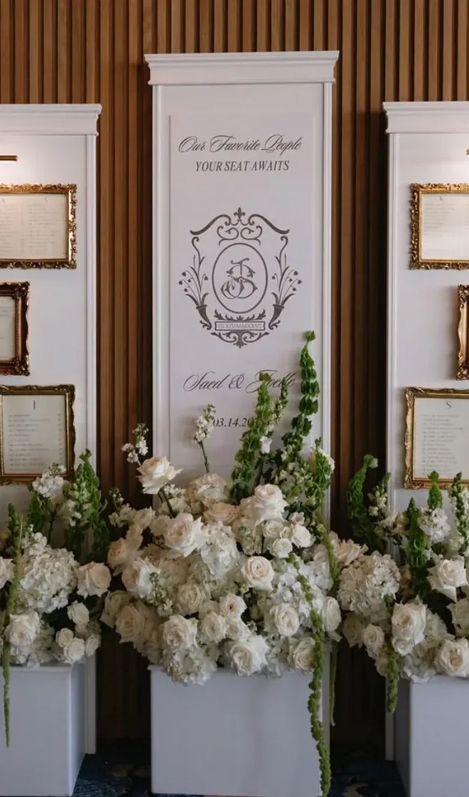 Custom welcome sign with monogram crest, framed by white florals