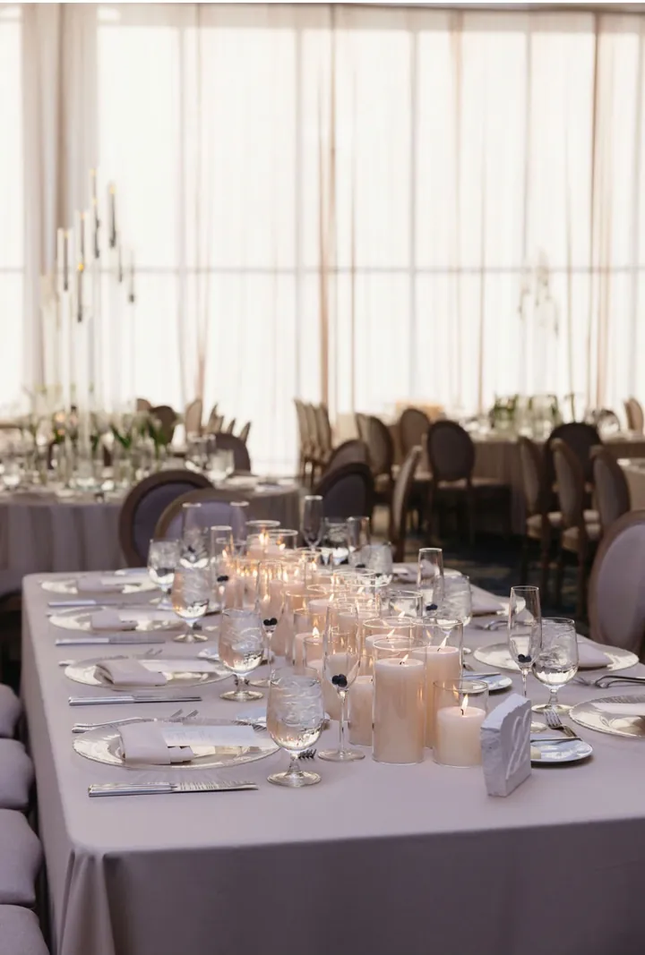 Long table lined with pillar candles in glass cylinders